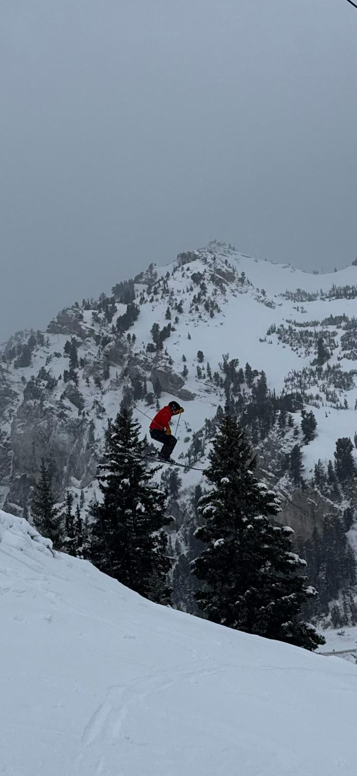 Canyon Whiteside jumping above snow-covered pines
